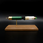 Front profile of an exploded Remington 12 Gauge AccuTip slug display featuring the green hull, exposed simulated powder, sabot, copper slug with green polymer tip, and expanded primer assembly with primer cup, anvil, and battery cup mounted on a handcrafted walnut wood presentation base.