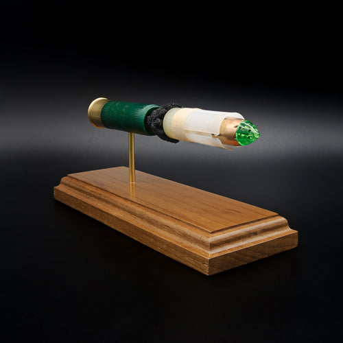 Right-front angle of an inert Remington 12 Gauge AccuTip shotgun shell display highlighting the sabot-encased slug, green polymer tip, exposed simulated powder, expanded primer assembly, and handcrafted walnut wood base.