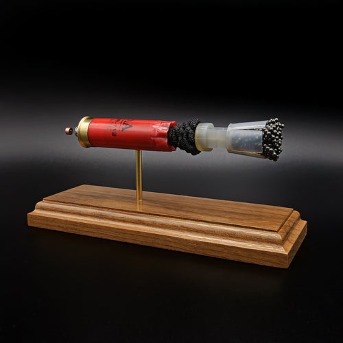 Front-right three-quarter view of a handcrafted Winchester AA 12 Gauge 7.5 Shot display showcasing the red hull, exposed simulated powder, wad, #7.5 lead shot payload, expanded primer cup, anvil, battery cup, and walnut presentation base.