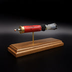 Rear-left three-quarter view of an exploded Winchester AA 12 Gauge 7.5 Shot display emphasizing the brass headstamp, expanded primer cup, anvil, battery cup, red hull, simulated powder, wad, and #7.5 lead shot payload on a walnut presentation base.