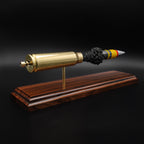 Rear angle of a 20mm Vulcan SAPHEI cartridge model showing the base of the casing and primer assembly mounted on a rosewood display