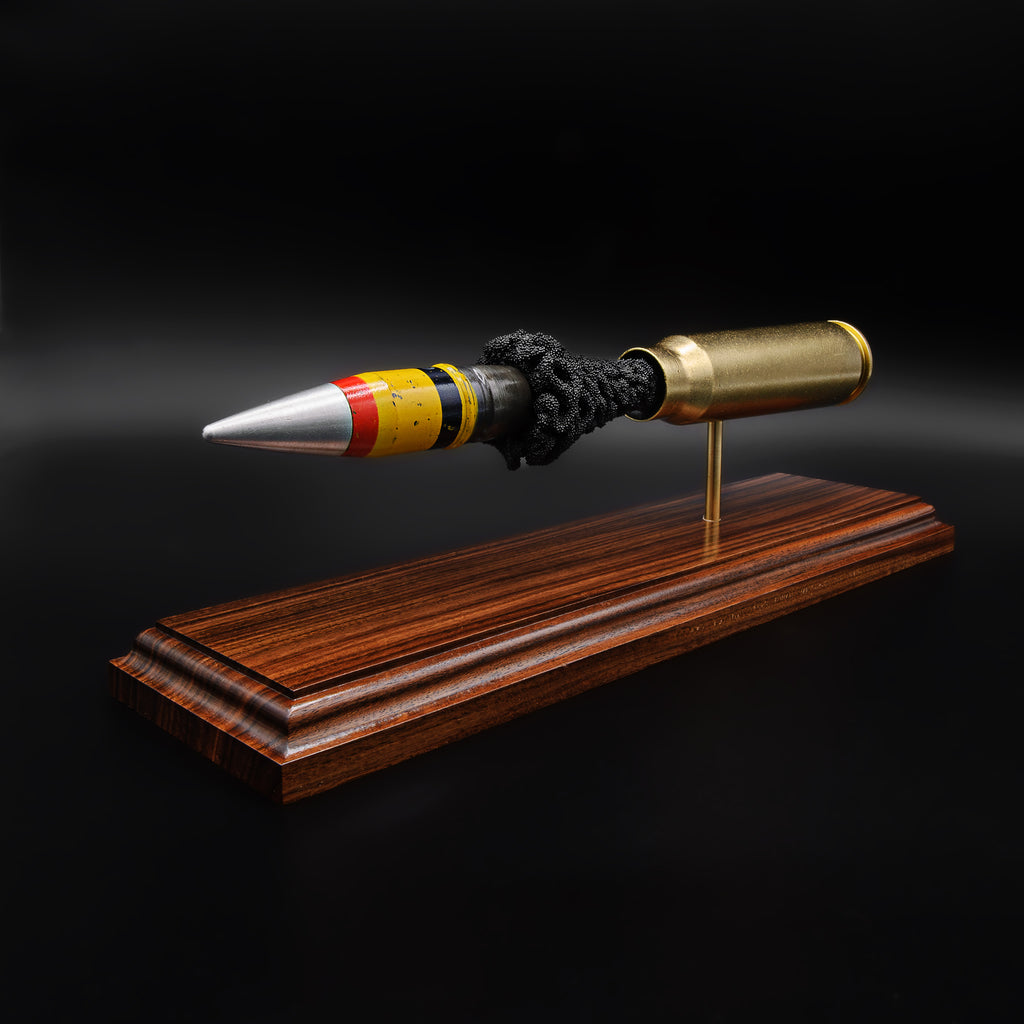 Front angled view of a 20mm Vulcan SAPHEI projectile with colored bands, positioned ahead of the casing on a rosewood base