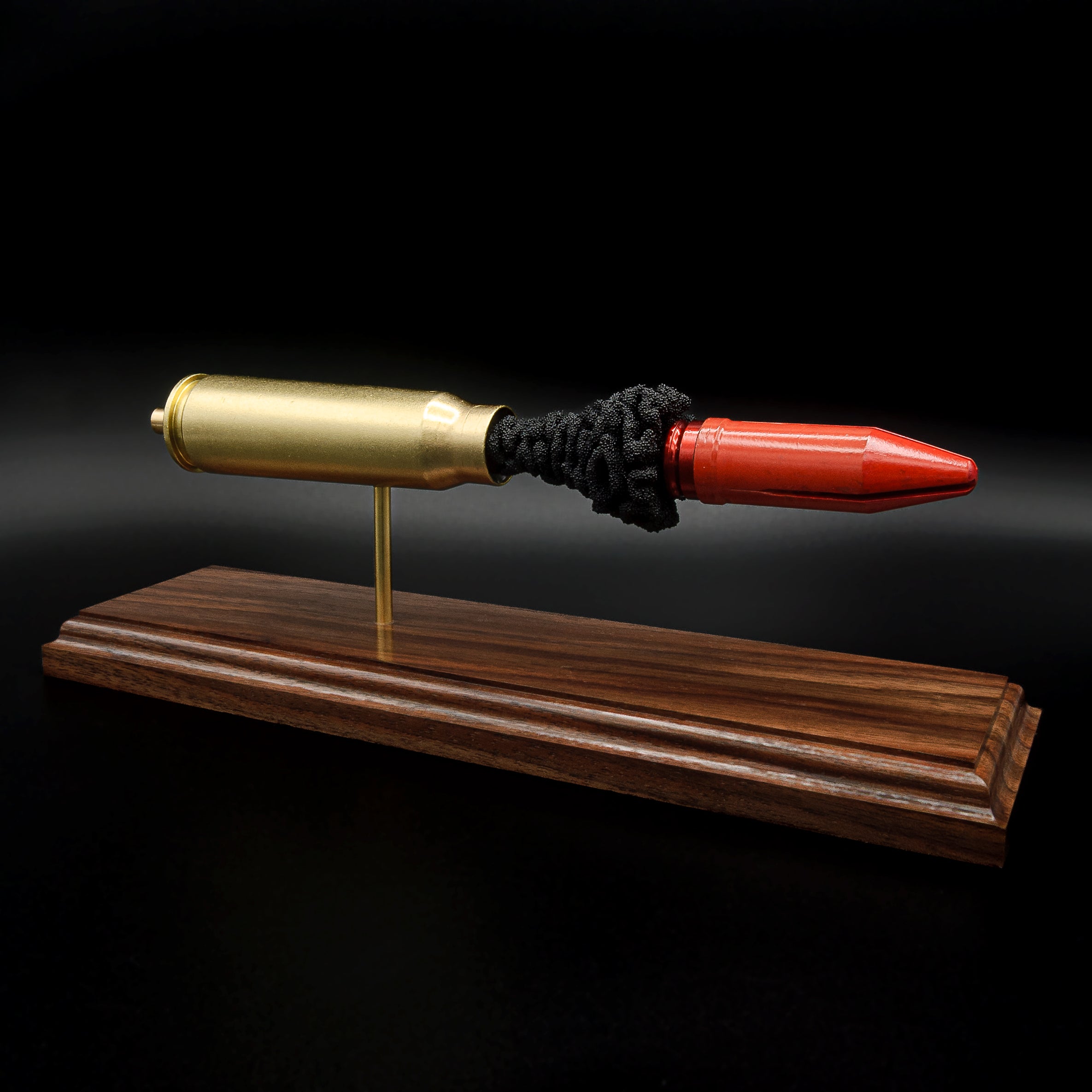 Side view of a 20mm Vulcan MK244 APDS anatomy cartridge display with exposed penetrator and simulated powder on walnut base