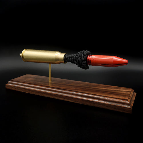 Side view of a 20mm Vulcan MK244 APDS anatomy cartridge display with exposed penetrator and simulated powder on walnut base