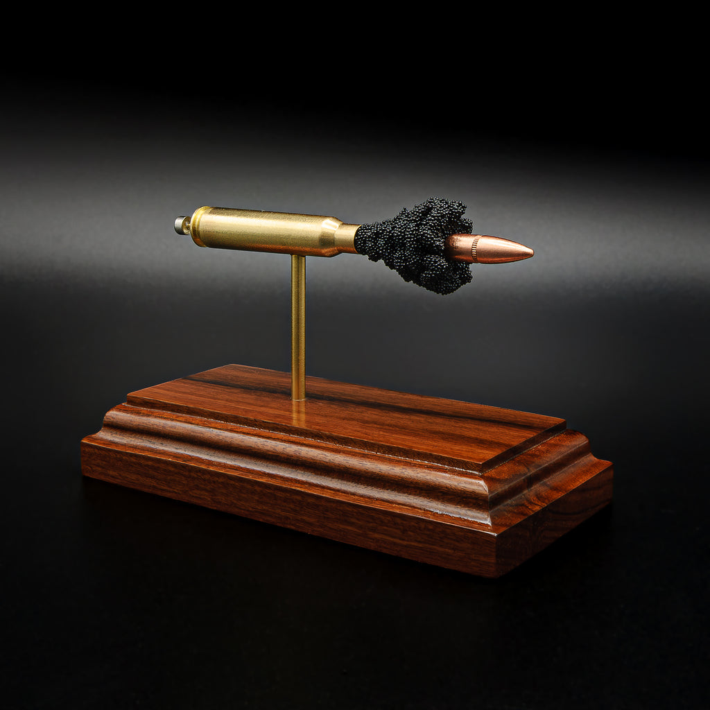 Front three-quarter view of an exploded .223 Remington FMJ cartridge display featuring the separated bullet, brass case, primer assembly, simulated powder, and handcrafted Bolivian rosewood presentation base.