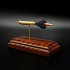 Front three-quarter view of an exploded .223 Remington FMJ cartridge display featuring the separated bullet, brass case, primer assembly, simulated powder, and handcrafted Bolivian rosewood presentation base.