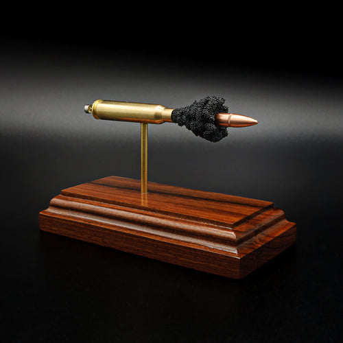 Front three-quarter view of an exploded .223 Remington FMJ cartridge display featuring the separated bullet, brass case, primer assembly, simulated powder, and handcrafted Bolivian rosewood presentation base.