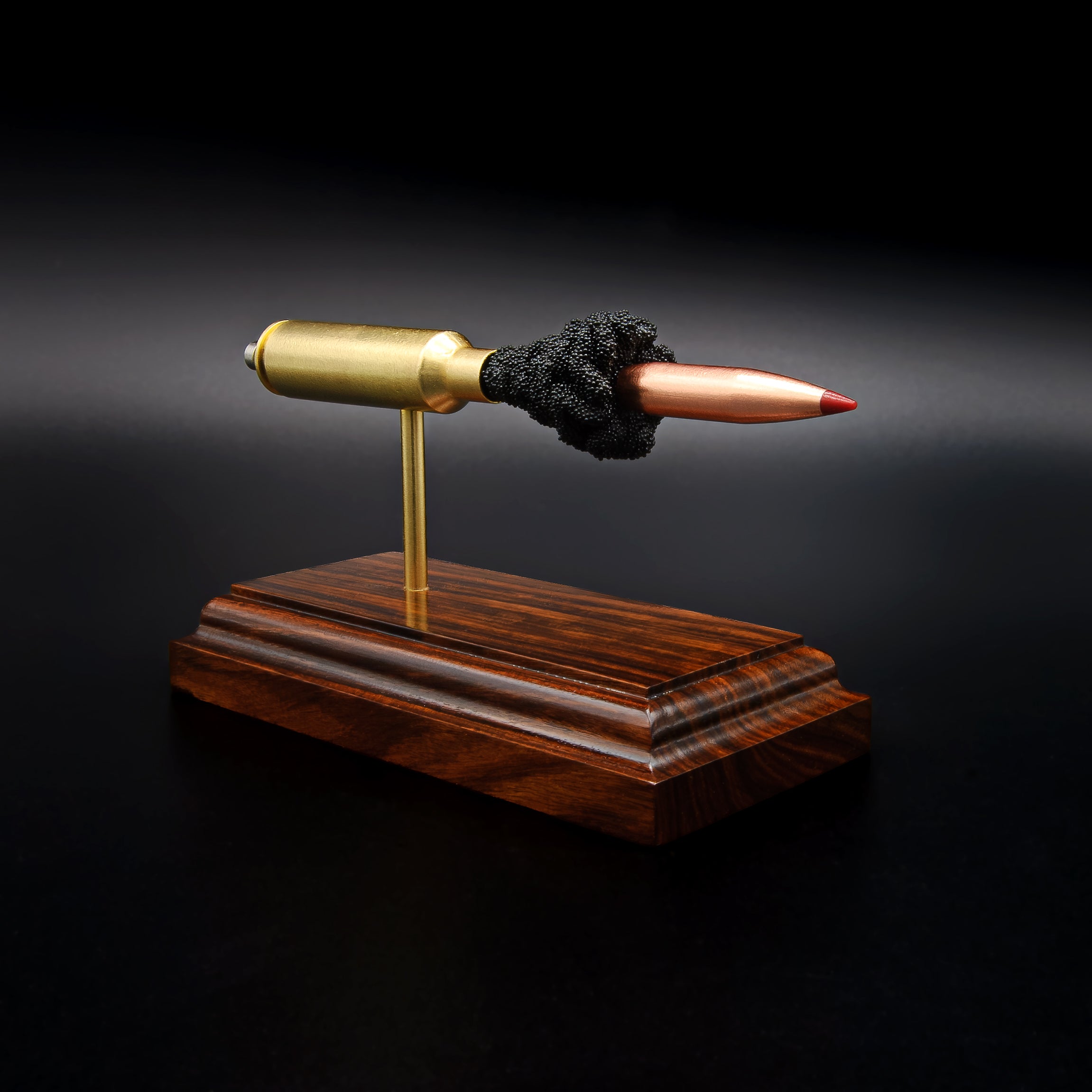 Side view of a .300 WSM cartridge anatomy display with the primer cup, anvil, cartridge case, simulated powder, and projectile clearly visible on a Bolivian rosewood base.
