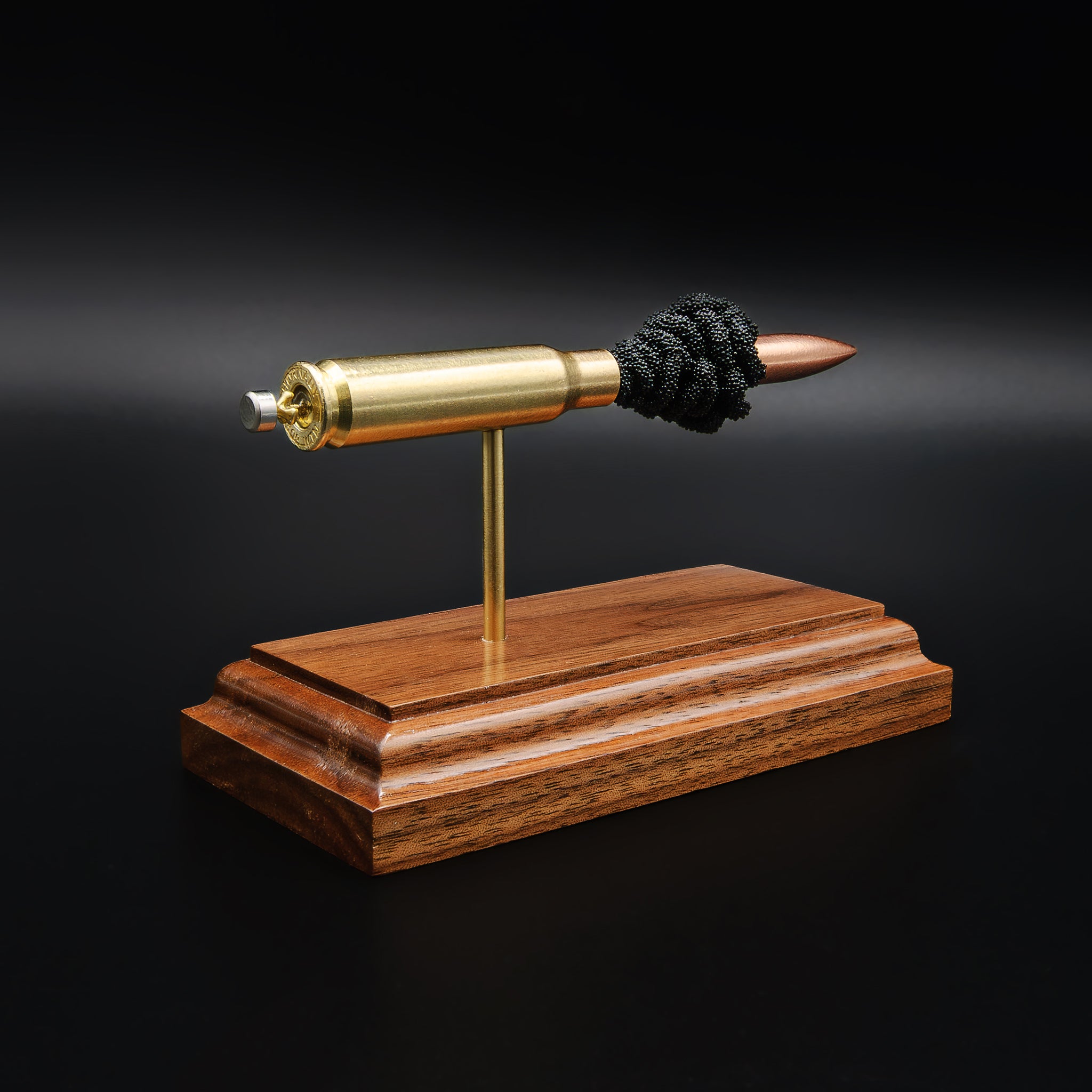 Rear view of 308 Winchester cartridge showing primer and case head on walnut base