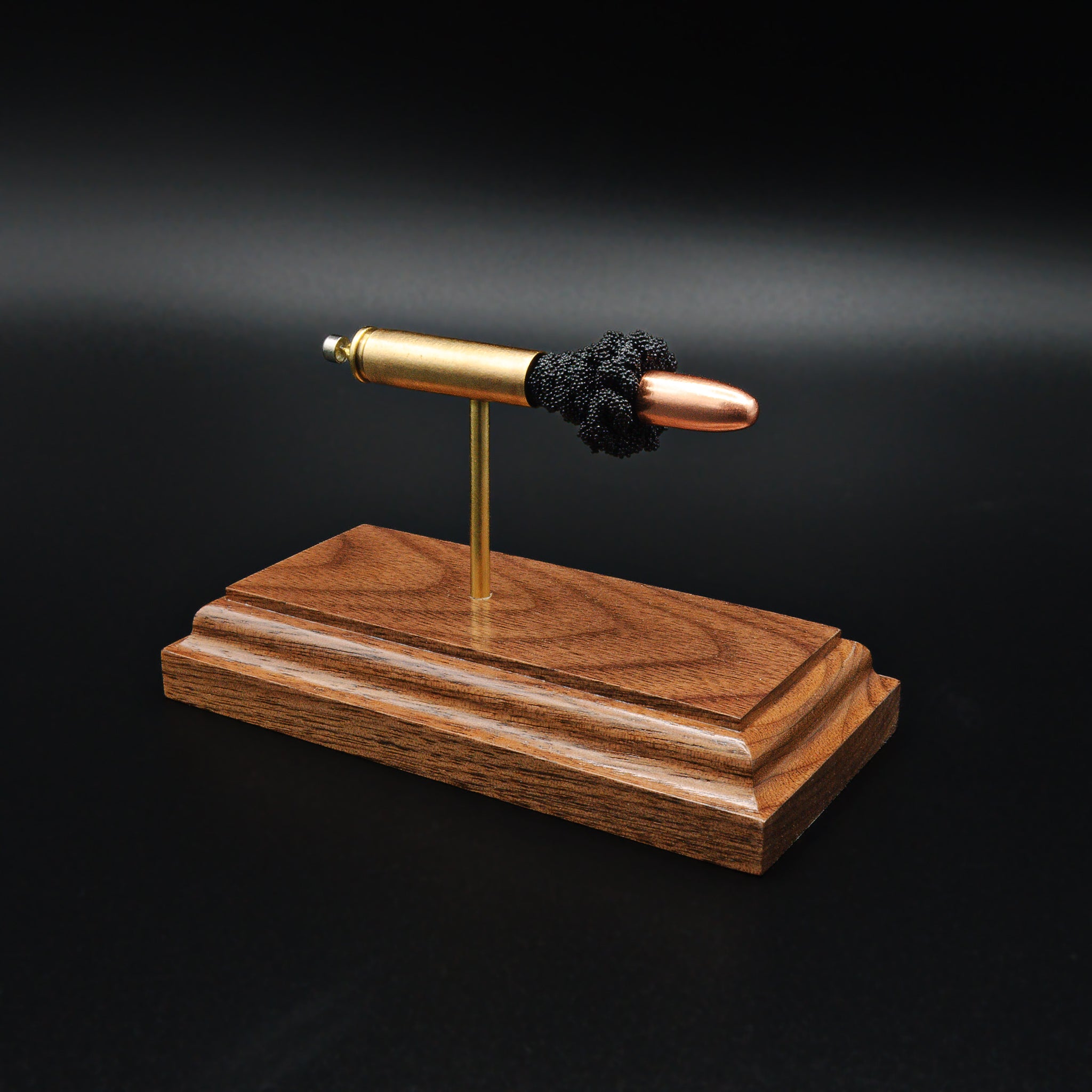 Angled view of 30 Carbine full metal jacket cartridge display on walnut base