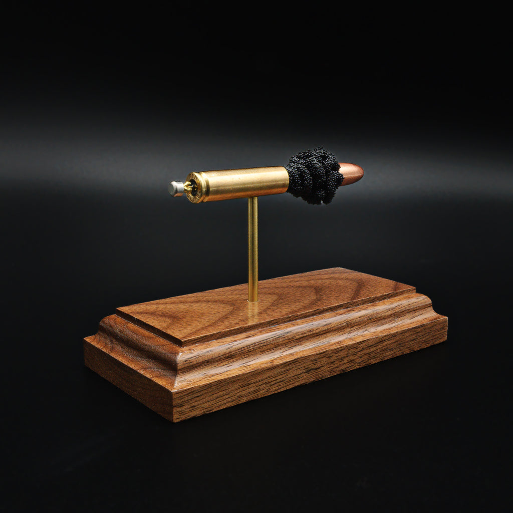 Rear view of 30 Carbine cartridge showing primer and case head on walnut base