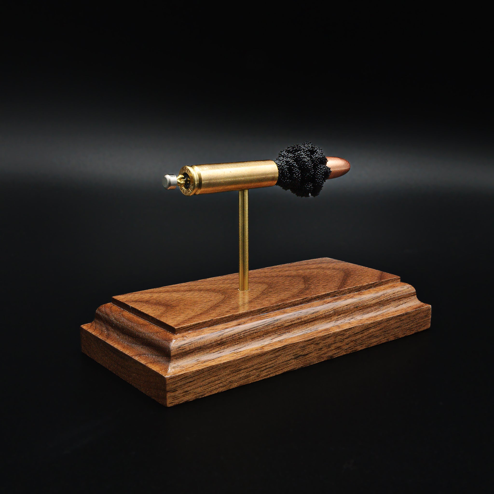Rear view of 30 Carbine cartridge showing primer and case head on walnut base
