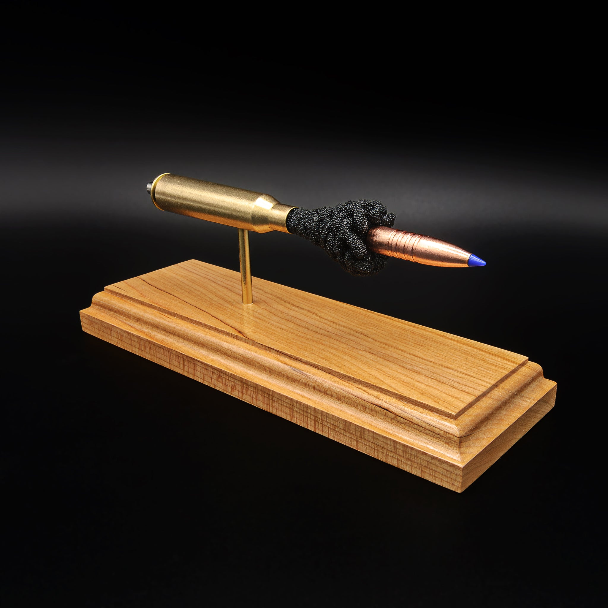 Angled view of .338 Lapua Magnum Barnes TTSX display with separated components mounted on cherry base