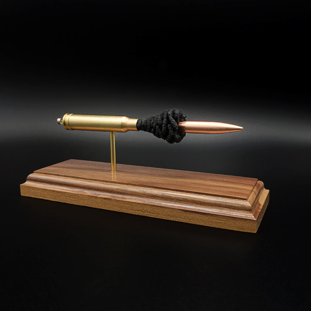 Front-left three-quarter view of an inert .338 Winchester Magnum anatomy cartridge display showcasing the Sierra MatchKing HPBT 300gr bullet and handcrafted walnut display base.