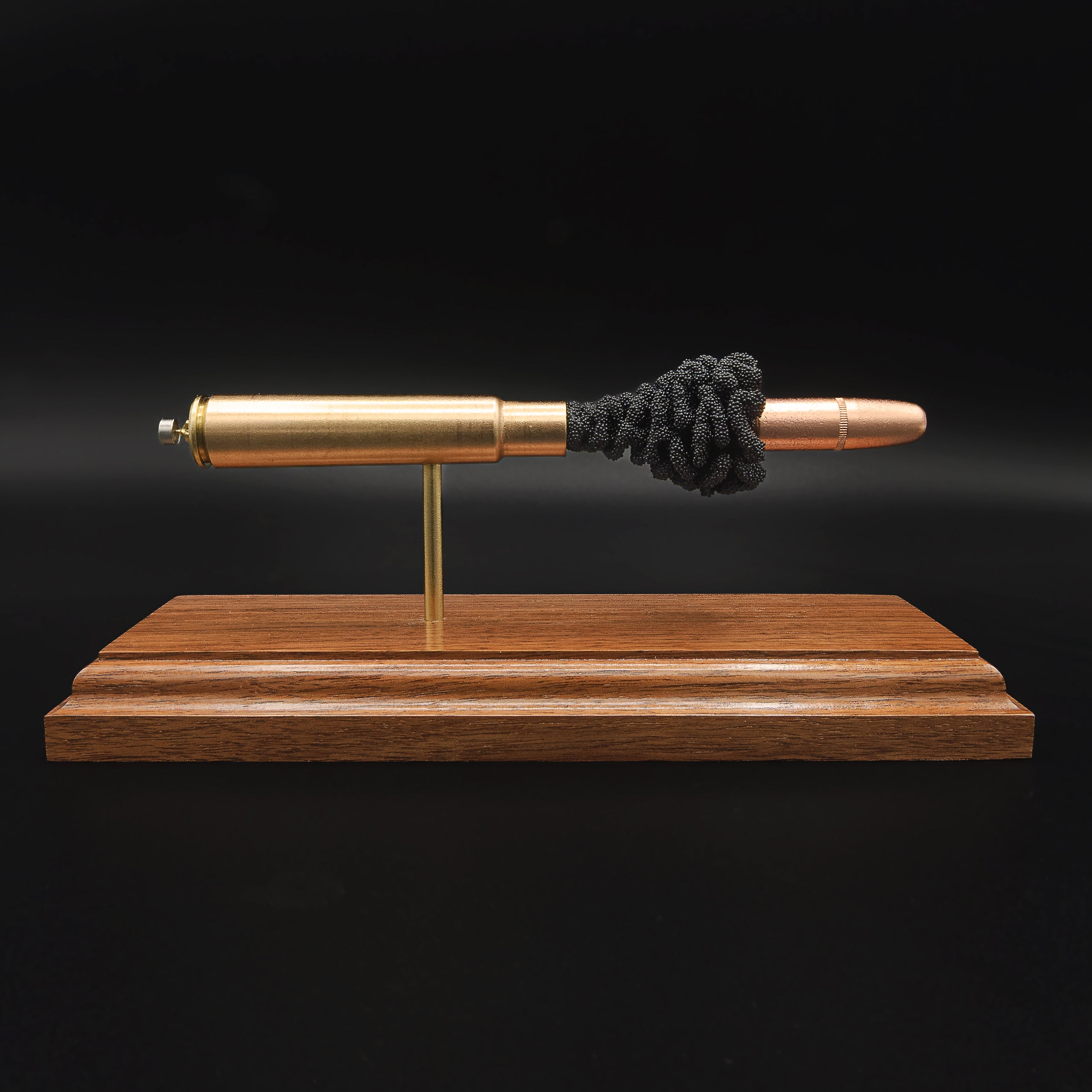 Front view of a .416 Rigby Hornady DGX cartridge anatomy display showing the primer cup, anvil, cartridge case, simulated powder, and projectile on a walnut wood base.