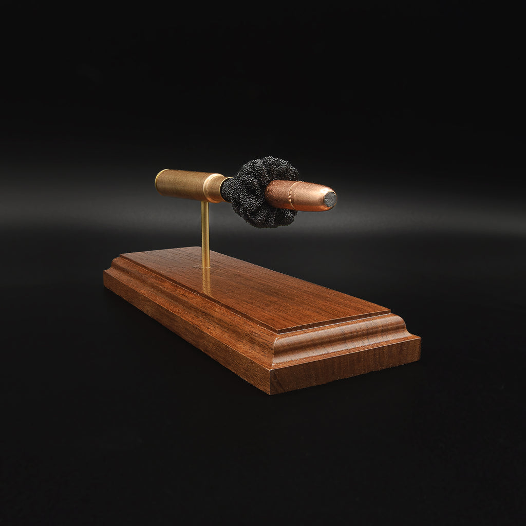 Side view of a .416 Rigby Hornady DGX cartridge anatomy display with the primer cup, anvil, cartridge case, simulated powder, and projectile visible on a walnut wood base.