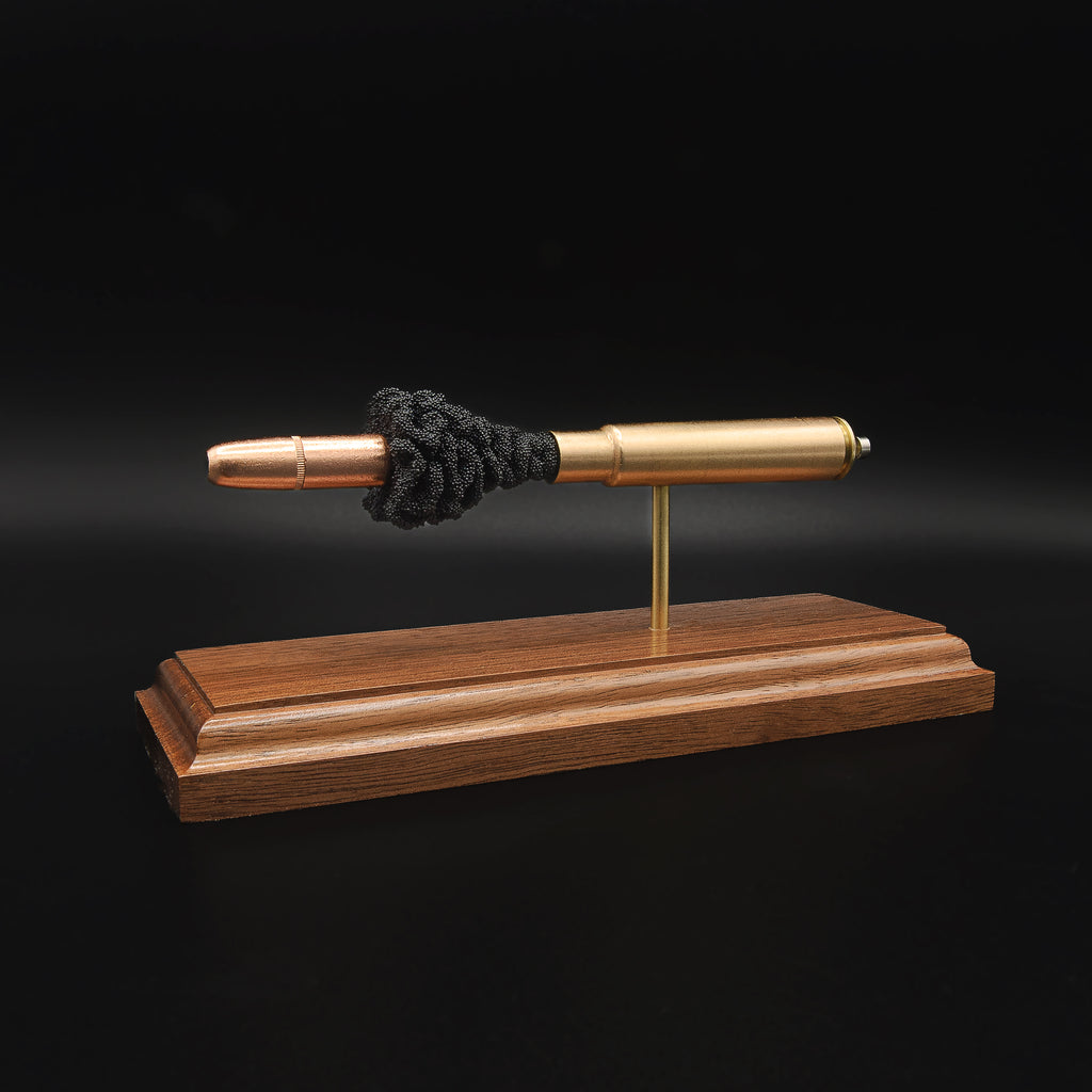 Angled rear view of a .416 Rigby Hornady DGX cartridge anatomy display featuring the primer cup, anvil, cartridge case, simulated powder, and projectile on a walnut wood base.