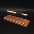 Close angled view of a .416 Rigby Hornady DGX cartridge anatomy display highlighting the DGX projectile, simulated powder, cartridge case, primer cup, and anvil on a walnut wood base.