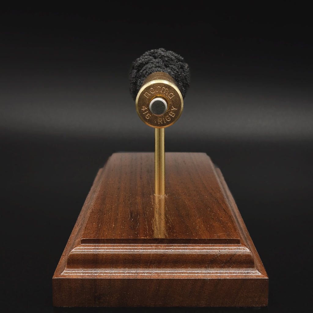 Rear view of a .416 Rigby Hornady DGX cartridge anatomy display showing the cartridge case head, primer cup, anvil, simulated powder, and projectile on a walnut wood base.