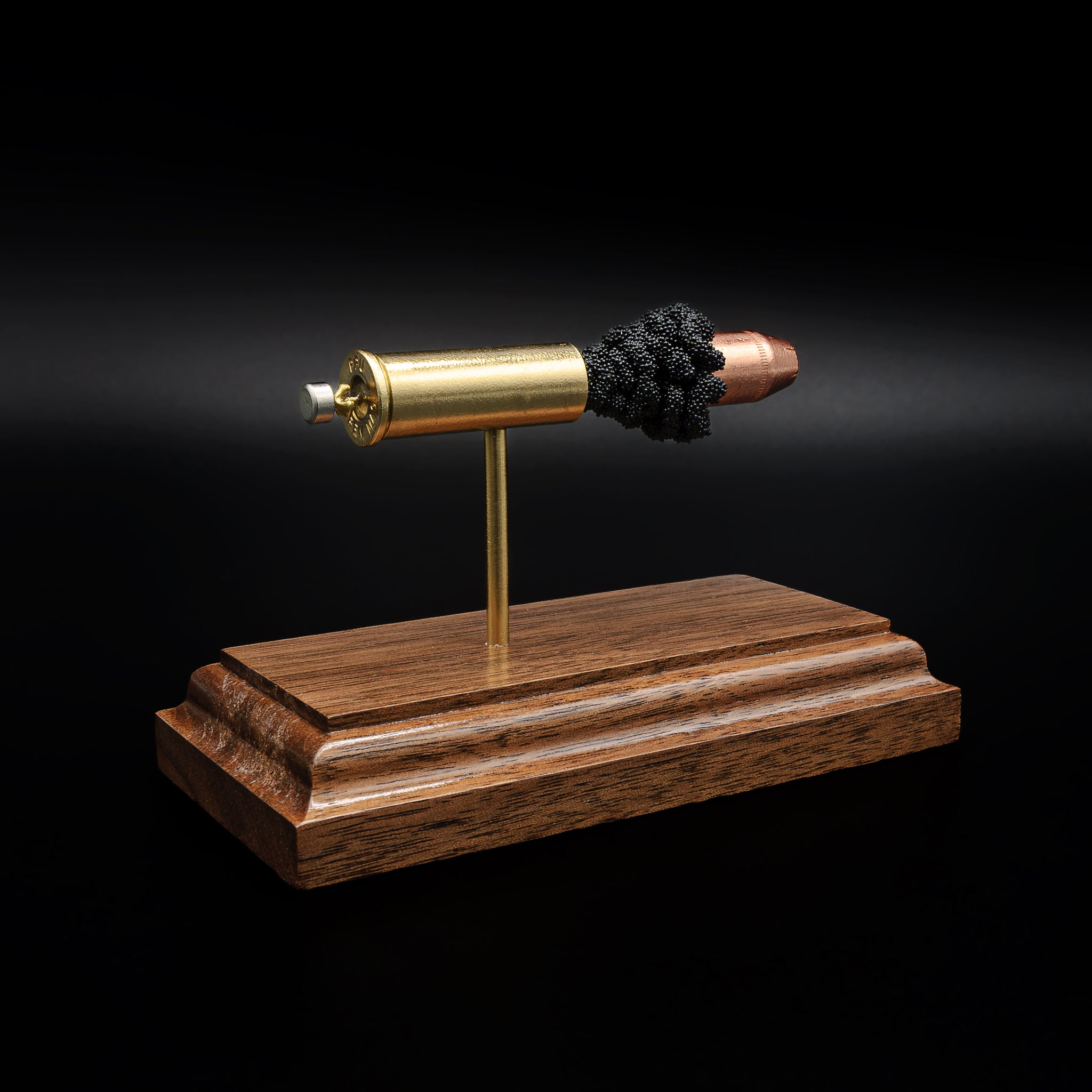 Rear view of a .44 Remington Magnum cartridge display showing the base of the casing and primer mounted above a walnut base