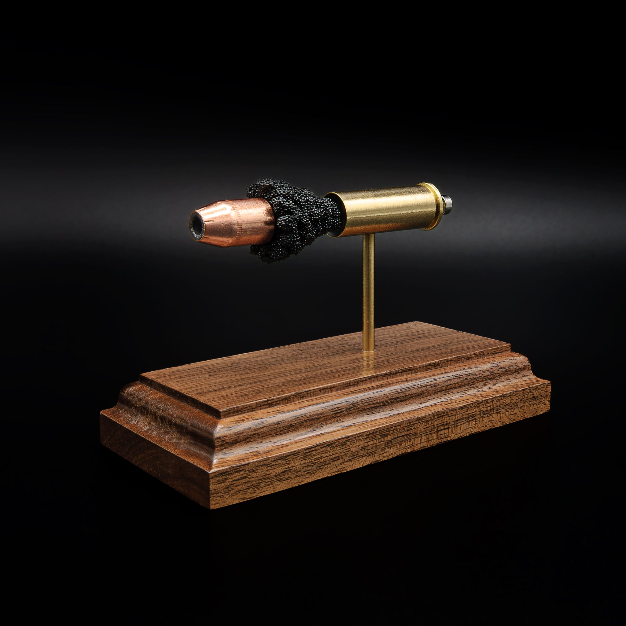 Front perspective of a .44 caliber hollow point bullet in an exploded cartridge display, mounted on a walnut base with visible powder texture