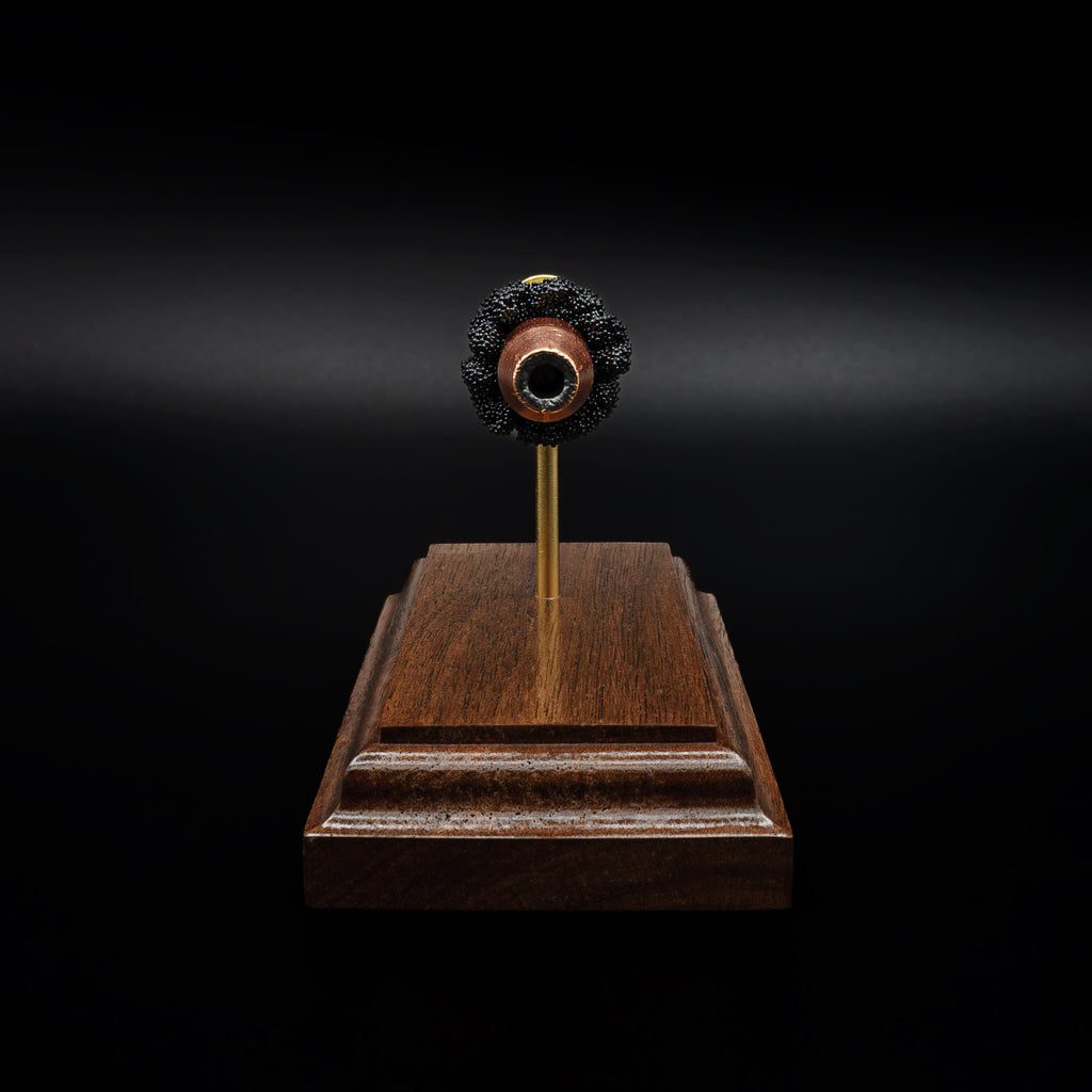 Head-on view of a .44 hollow point bullet centered above a walnut base, with the opening of the projectile clearly visible