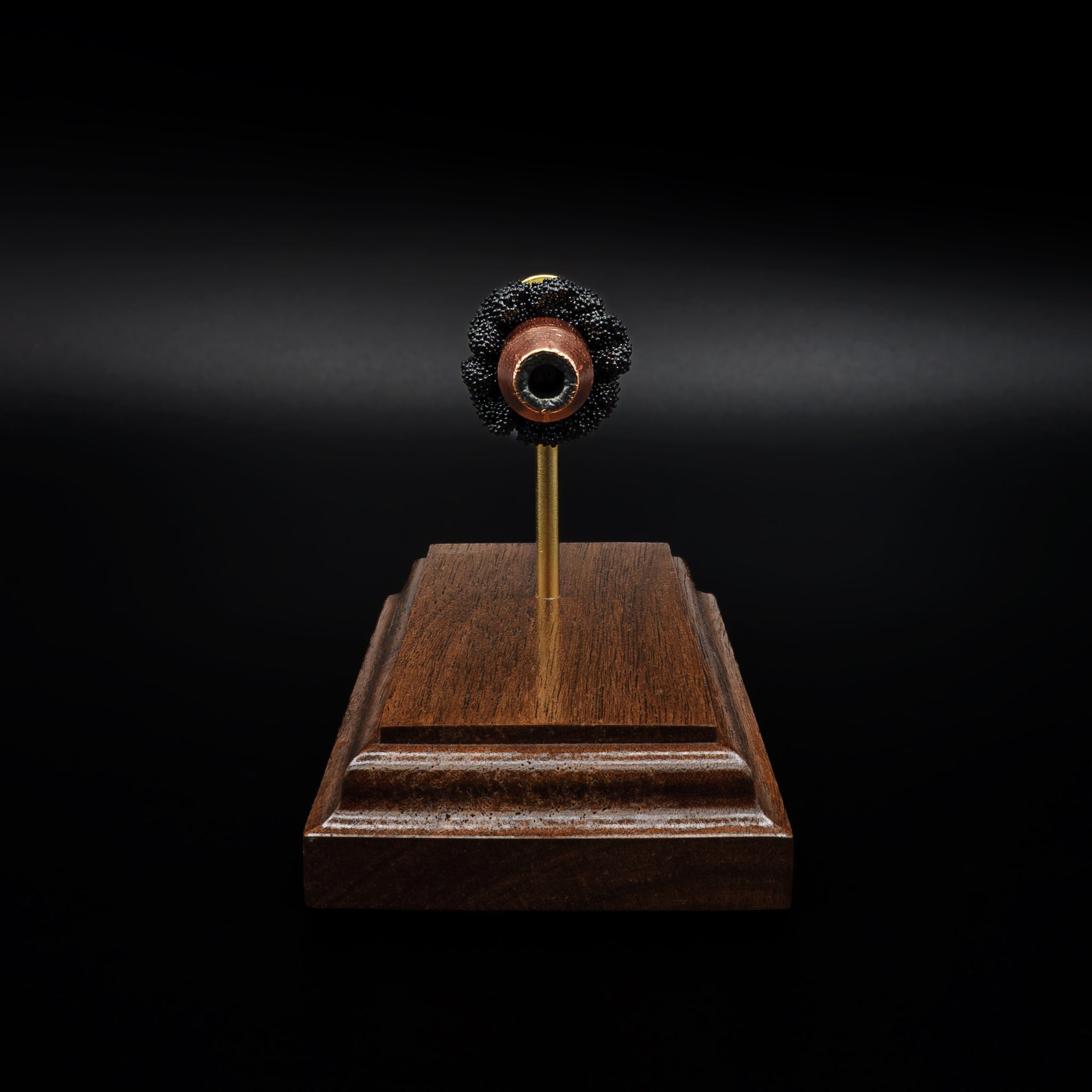 Head-on view of a .44 hollow point bullet centered above a walnut base, with the opening of the projectile clearly visible