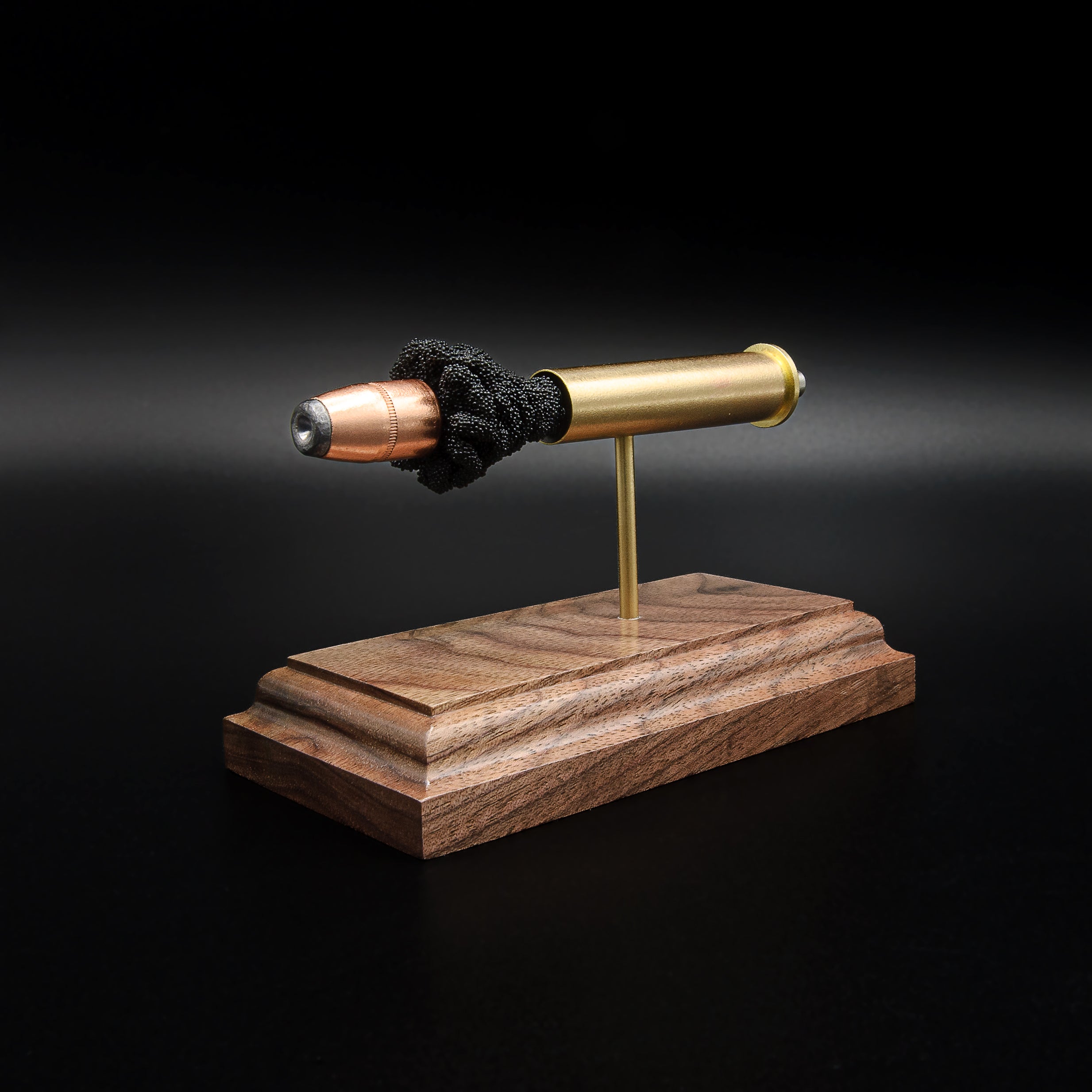 Left-rear perspective of a handcrafted .45-70 Government cartridge display featuring a brass case, Hornady InterLock HP bullet, and solid walnut base.