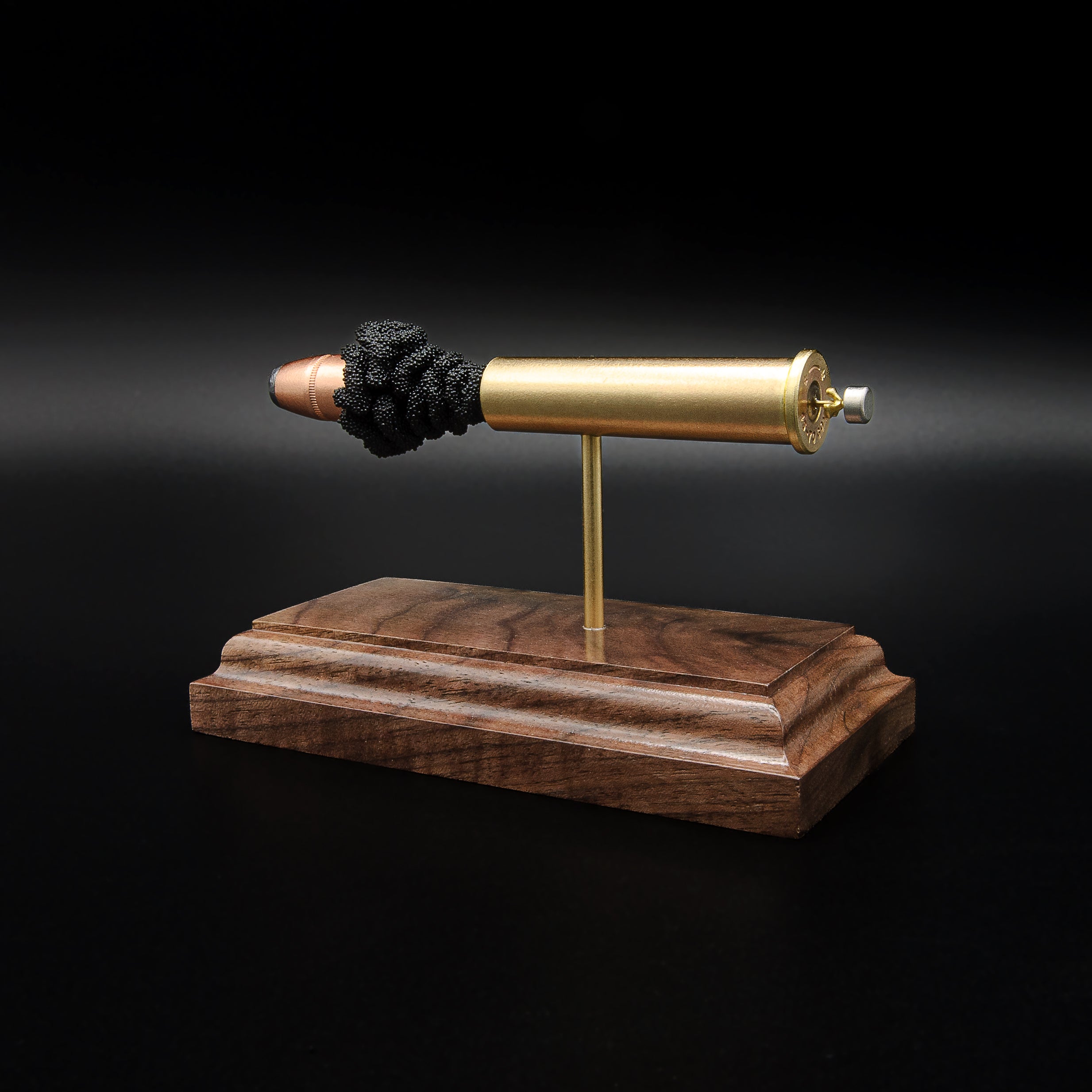 Rear three-quarter view of a .45-70 Government exploded cartridge display emphasizing the cartridge base, primer assembly, and walnut presentation stand.