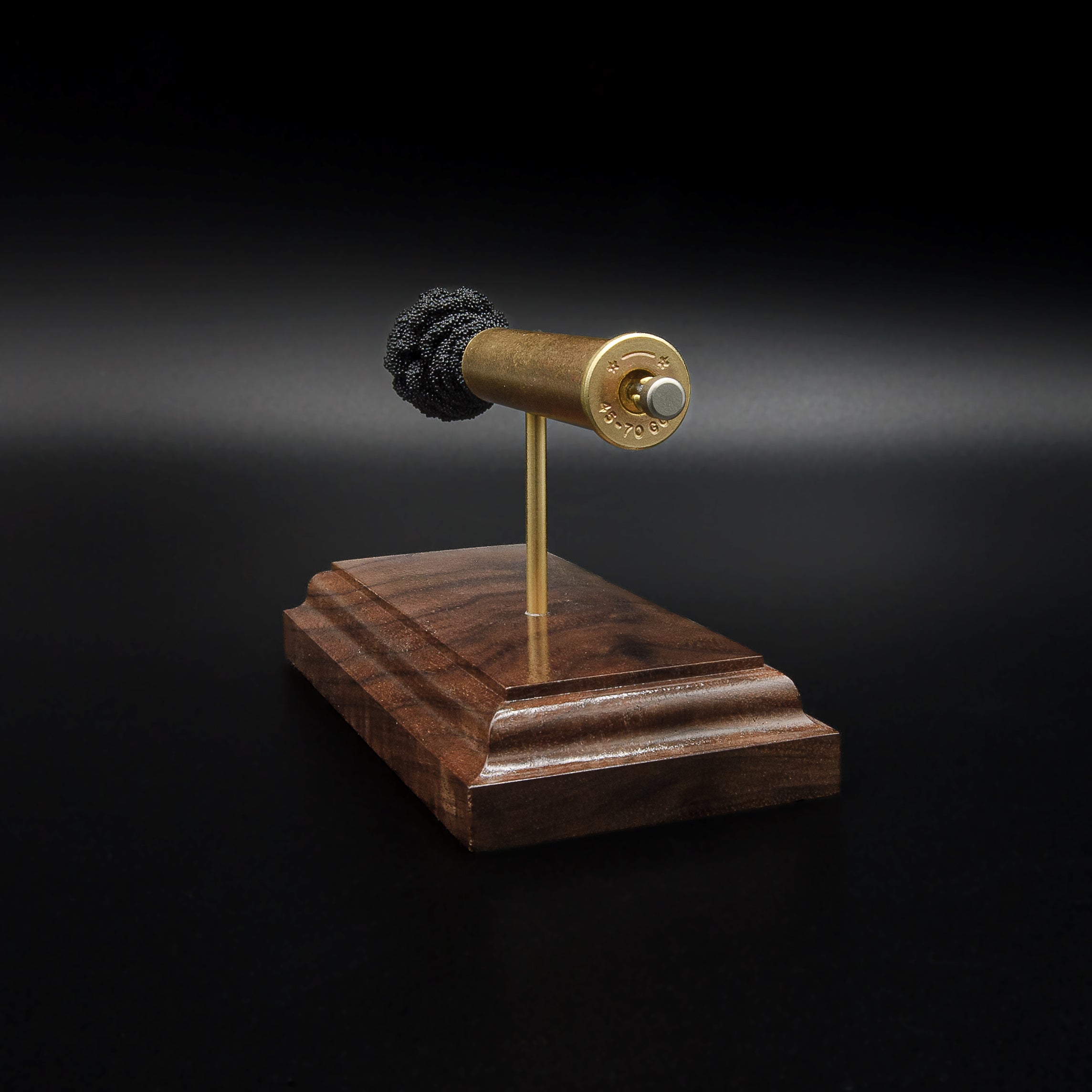 Close rear perspective of a .45-70 Government anatomy display highlighting the brass case head, primer details, and handcrafted walnut base.