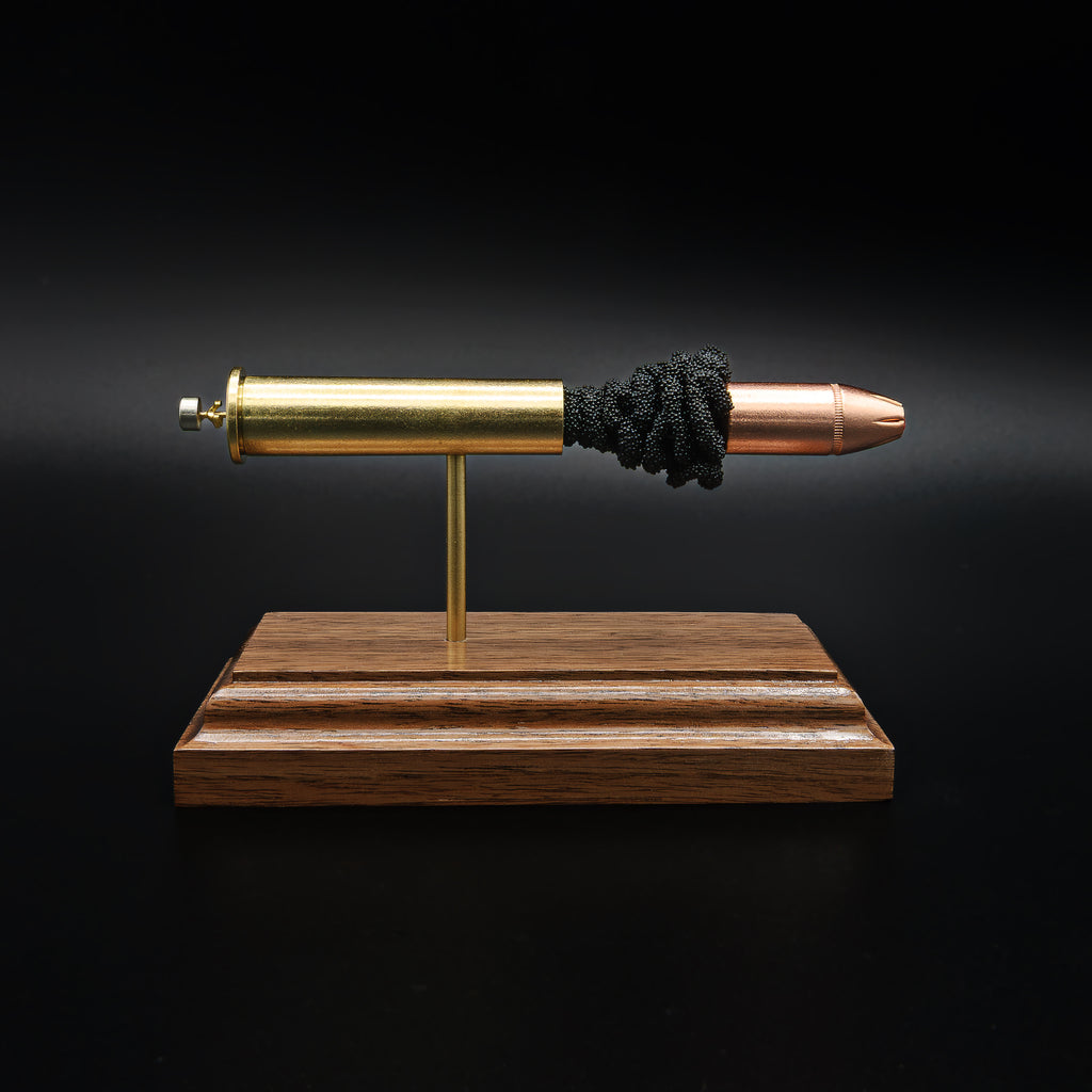 Front view of a 45-70 Government Hornady Sub-X 410gr cartridge anatomy display showing the primer cup, anvil, brass case, simulated powder, and projectile on a walnut base.
