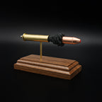 Front left angle of a 45-70 Government Hornady Sub-X 410gr cartridge anatomy display highlighting the exposed simulated powder, brass case, and polymer-tipped projectile on a walnut base.