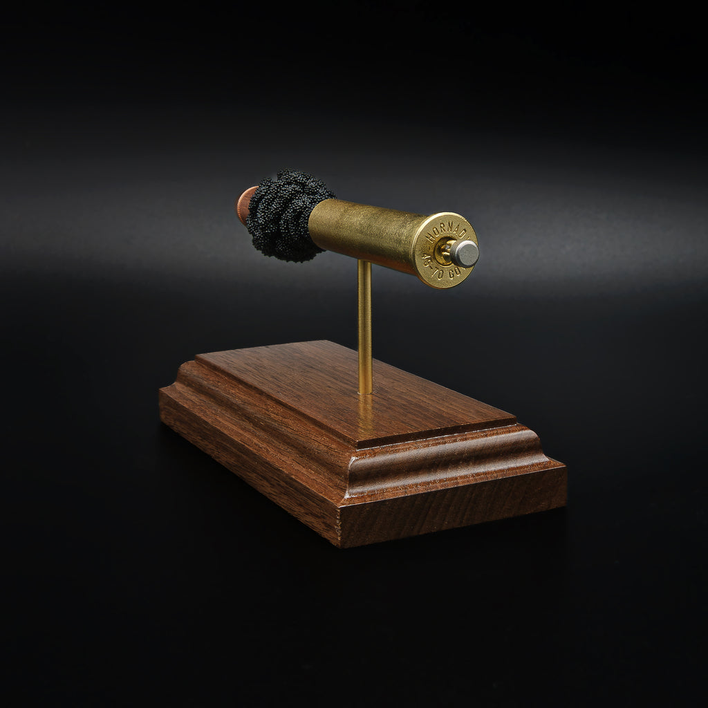 Rear view of a 45-70 Government Hornady Sub-X 410gr cartridge anatomy display featuring the cartridge head, brass case, simulated powder, and projectile on a walnut base.