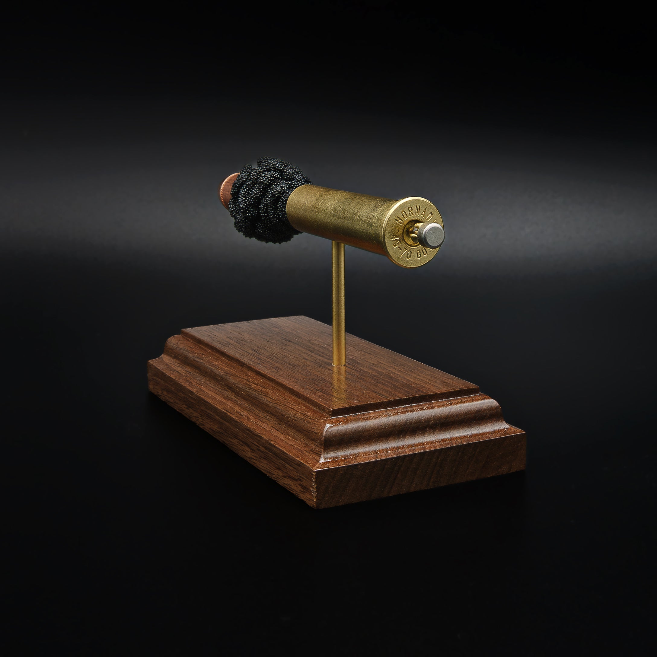 Rear view of a 45-70 Government Hornady Sub-X 410gr cartridge anatomy display featuring the cartridge head, brass case, simulated powder, and projectile on a walnut base.