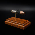 Angled view of a .45 Auto cartridge model on a rosewood base, highlighting the red polymer tip and textured powder between components