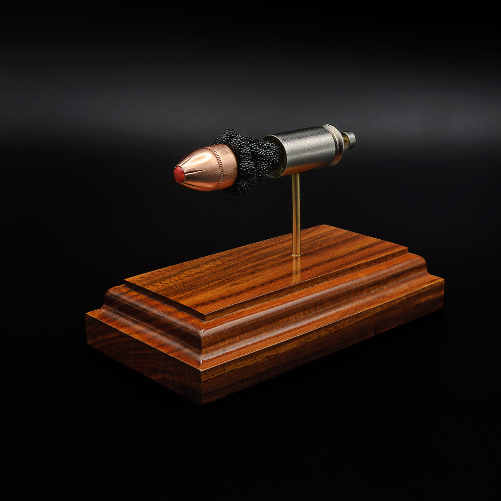 Front perspective of a .45 caliber polymer-tipped bullet in an exploded cartridge display, mounted on a rosewood base