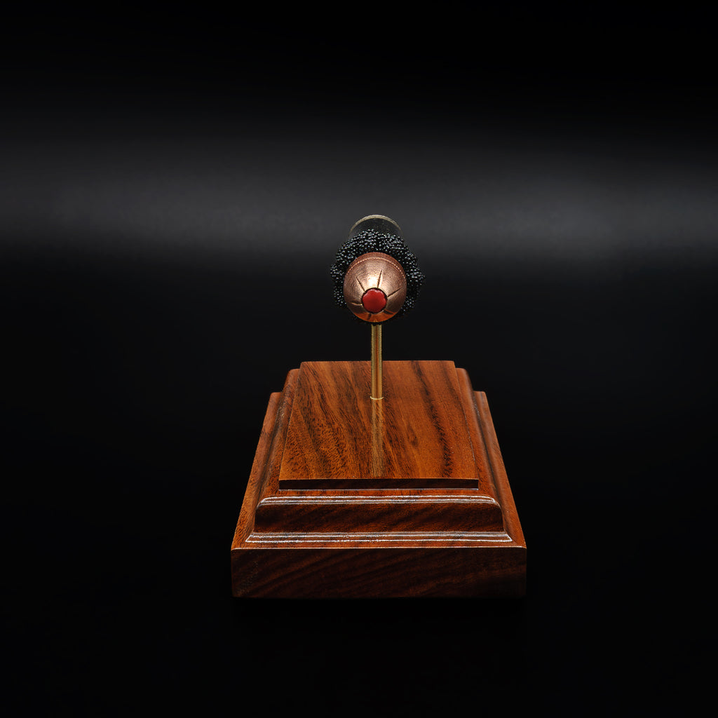 Head-on view of a .45 polymer-tipped bullet centered above a rosewood base, with the red tip clearly visible