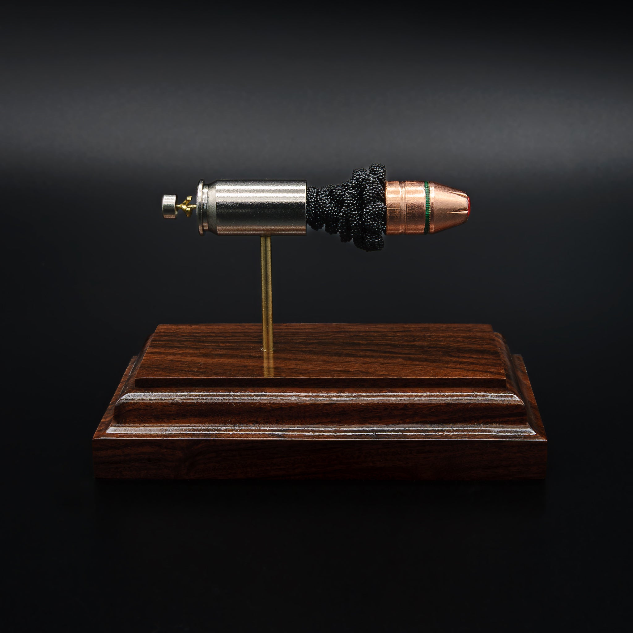 A .45 Auto cartridge displayed in an exploded layout on a rosewood base, featuring a nickel case, powder cluster, and Hornady Critical Duty bullet with FlexLock tip aligned in a straight line