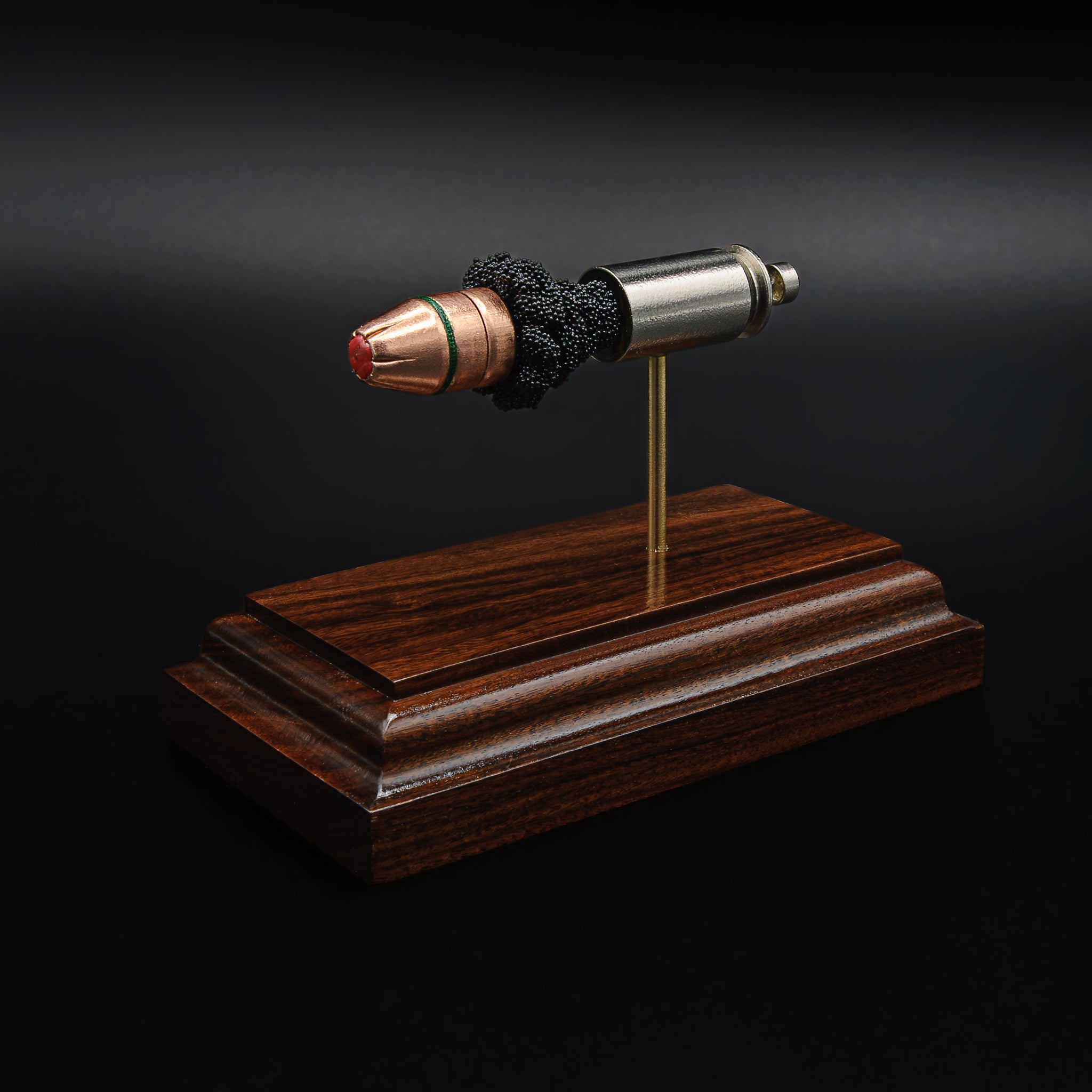 Angled view of a .45 Auto Critical Duty cartridge model on a rosewood base, highlighting the red FlexLock tip and green sealant band