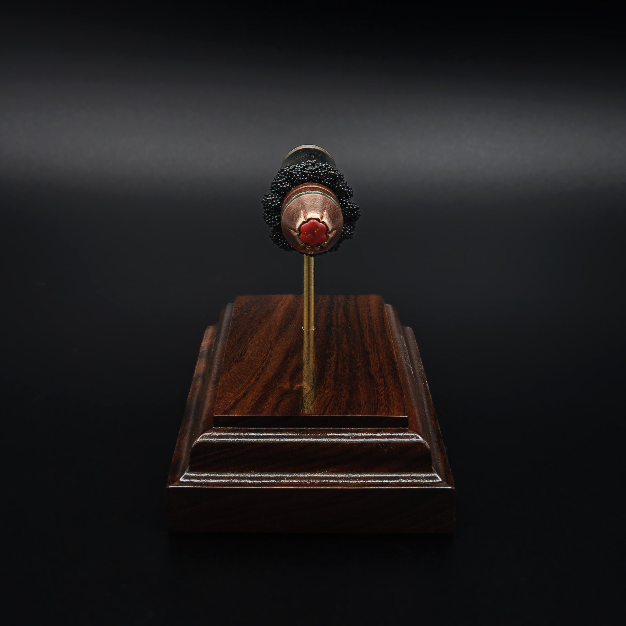 Head-on view of a .45 FlexLock bullet centered above a rosewood base, with the red tip and jacket design clearly visible