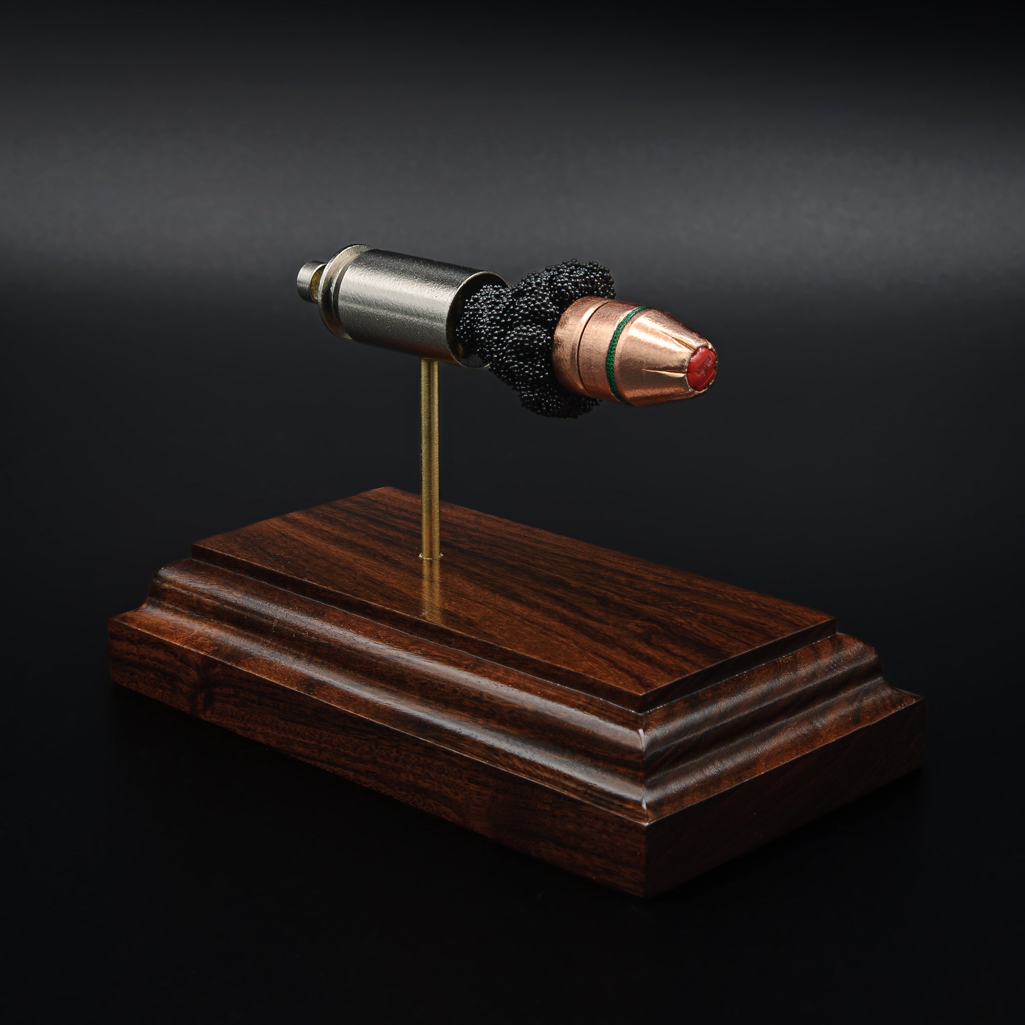 Angled view of a .45 Auto Critical Duty cartridge model on a rosewood base, highlighting the red FlexLock tip and green sealant band