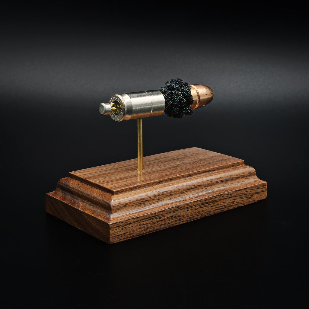 Side view of a .45 Auto Federal 230gr HST JHP cartridge anatomy display with the primer cup, anvil, cartridge case, simulated powder, and projectile visible on a walnut wood base.