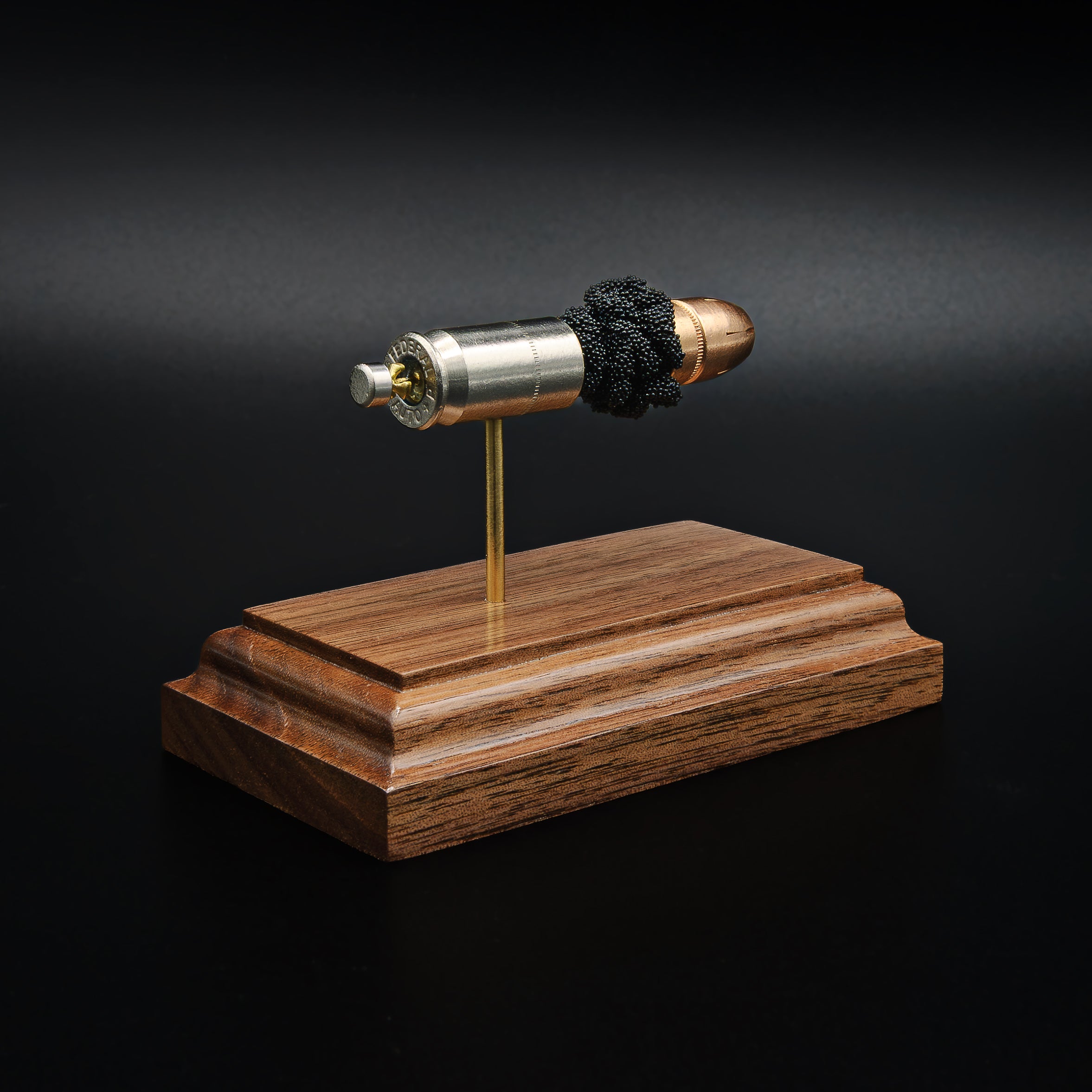 Side view of a .45 Auto Federal 230gr HST JHP cartridge anatomy display with the primer cup, anvil, cartridge case, simulated powder, and projectile visible on a walnut wood base.
