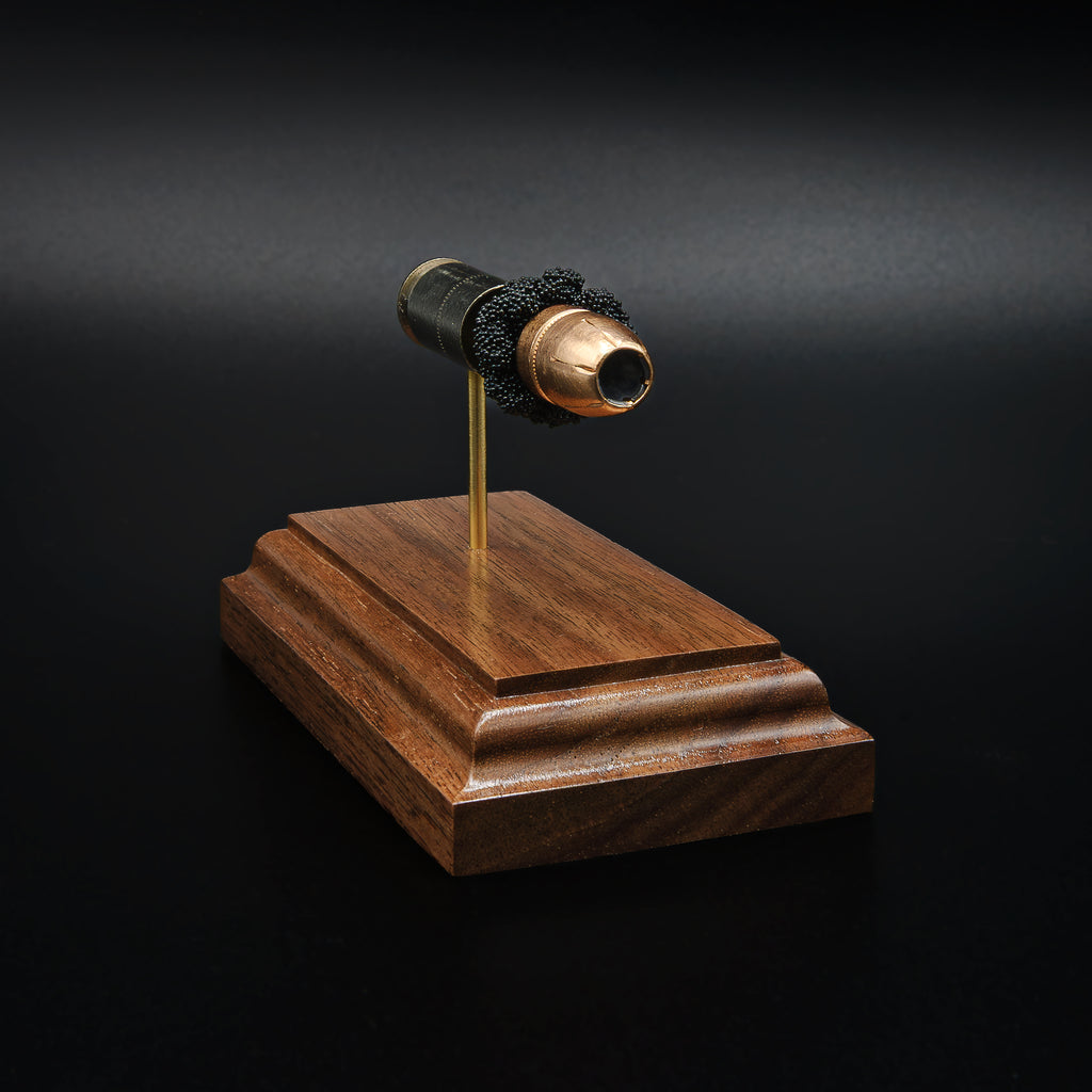 Front angled view of a .45 Auto Federal 230gr HST JHP cartridge anatomy display with the primer cup, anvil, cartridge case, simulated powder, and projectile mounted on a walnut wood base.