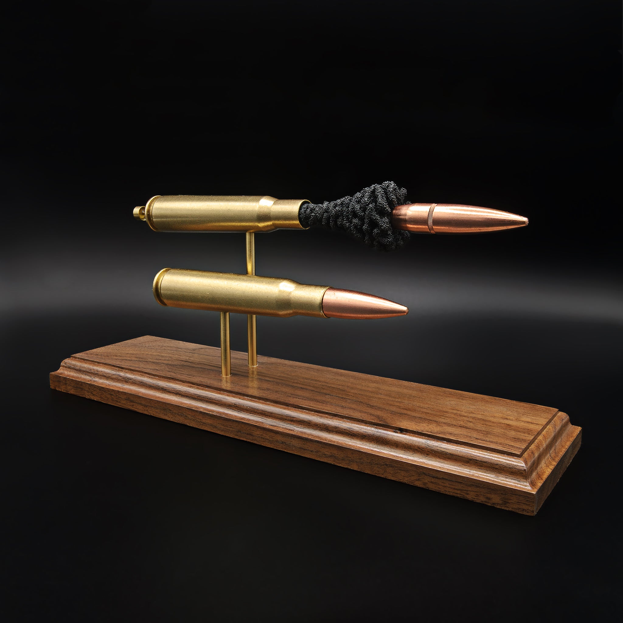 Angled view of .50 BMG cartridge comparison with full round and exploded components mounted on a walnut base