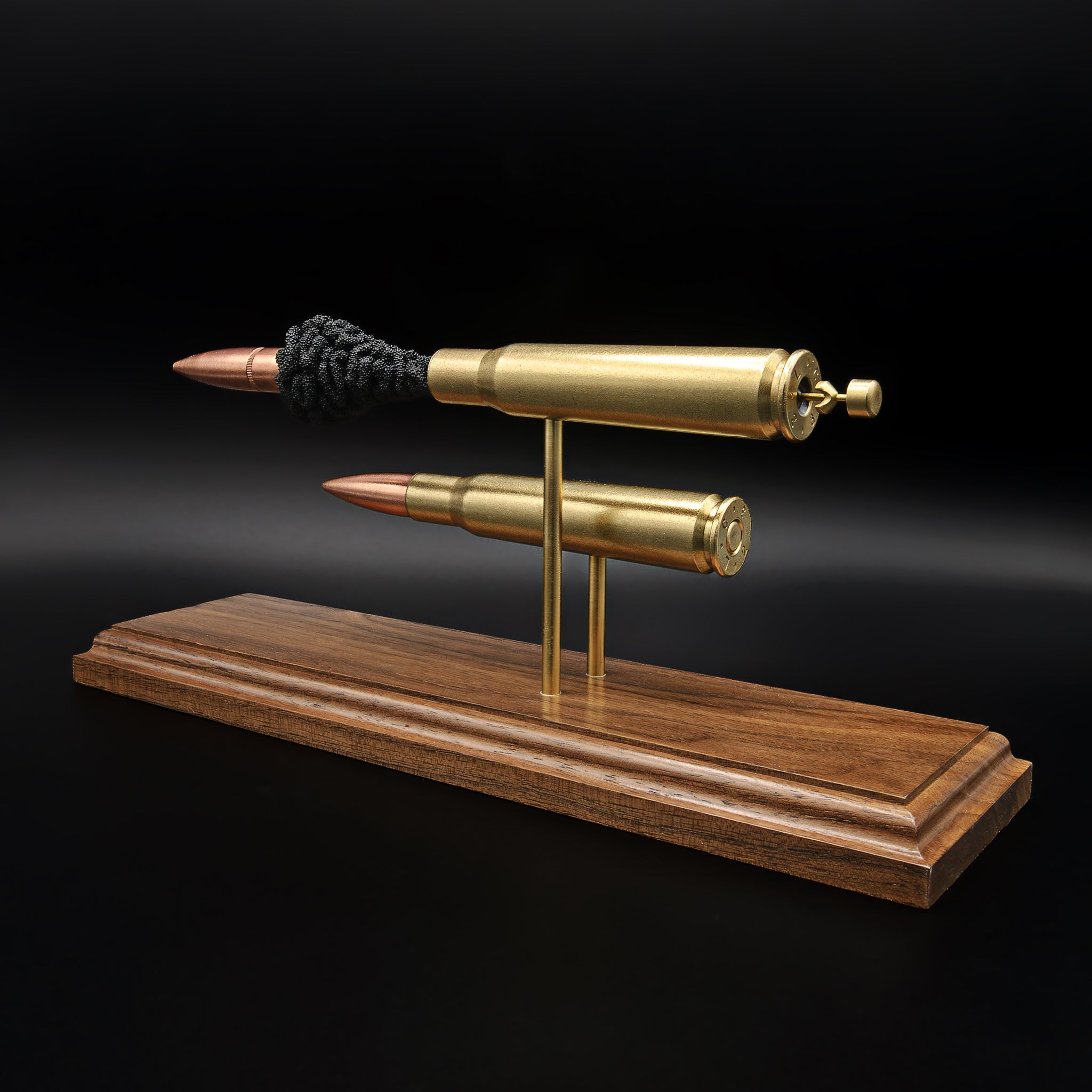 Back perspective of .50 BMG cartridge comparison display highlighting casing headstamps and dual mounting on walnut base