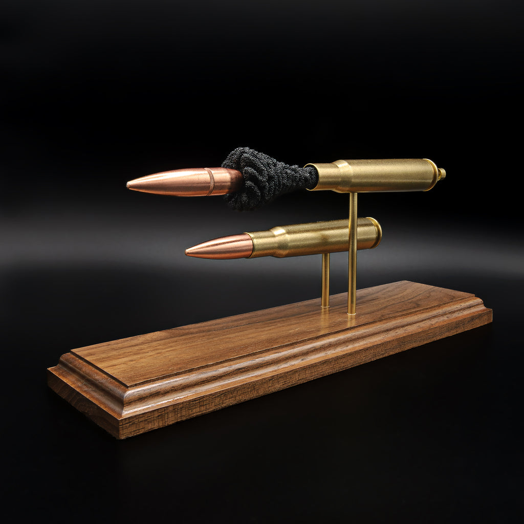 Front angled view of .50 BMG bullets in comparison display showing full cartridge and exploded anatomy on walnut base