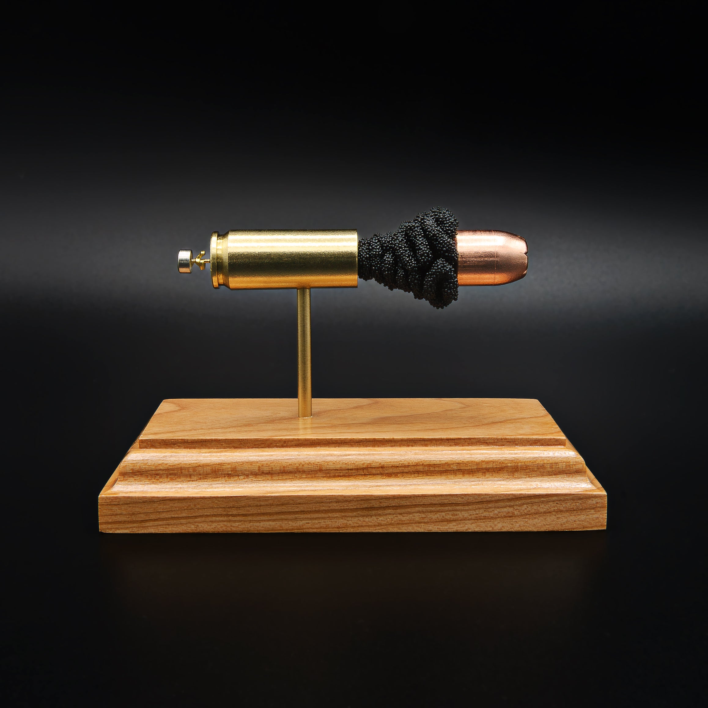 Front view of a .50 Action Express Hornady Custom 300gr XTP cartridge anatomy display showing the primer cup, anvil, cartridge case, simulated powder, and projectile on a cherry wood base.