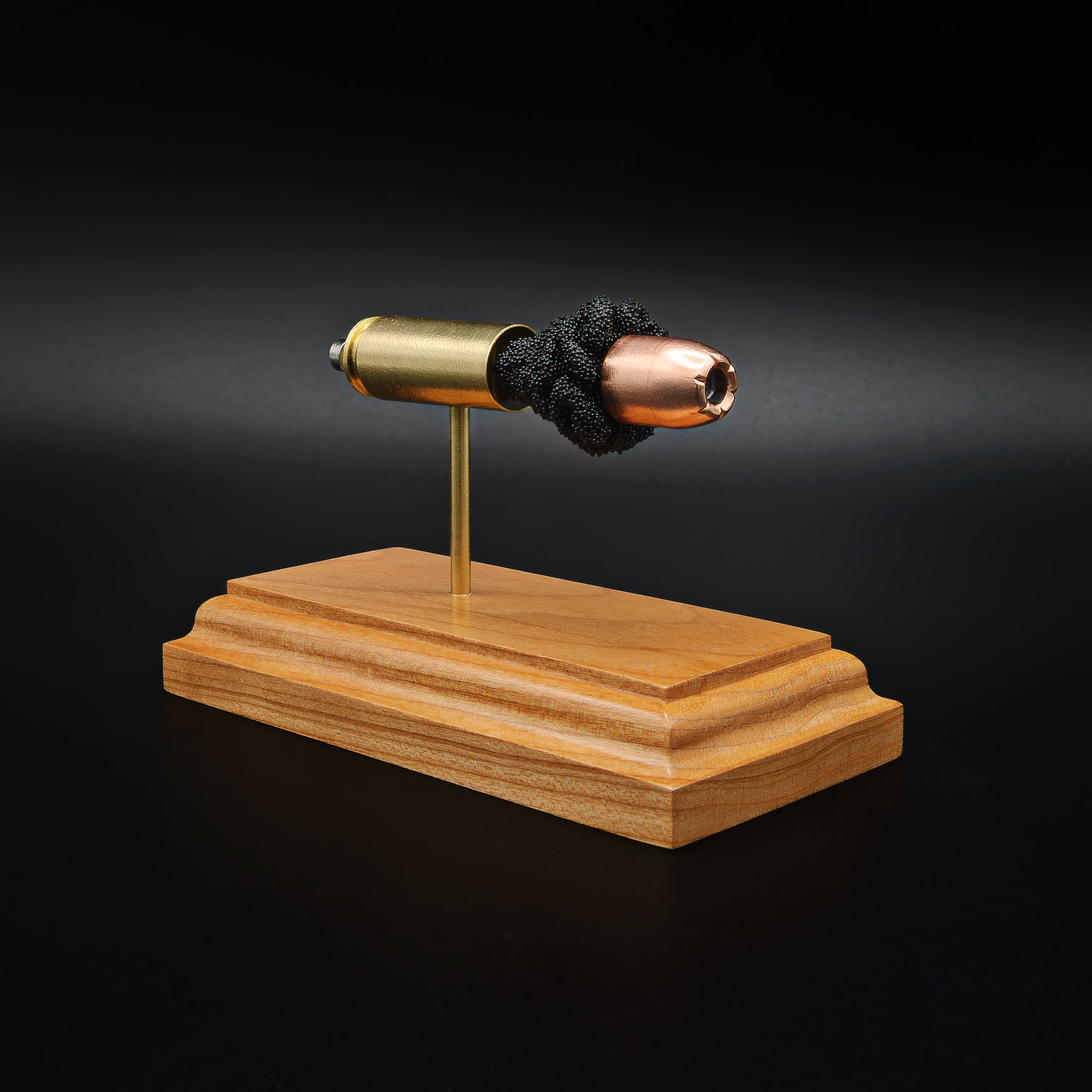 Side view of a .50 Action Express Hornady Custom 300gr XTP cartridge anatomy display with the primer cup, anvil, cartridge case, simulated powder, and projectile visible on a cherry wood base.