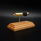 Rear view of a .50 Action Express Hornady Custom 300gr XTP cartridge anatomy display showing the cartridge case head, primer cup, anvil, simulated powder, and projectile on a cherry wood base.